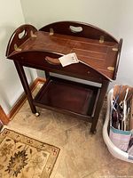 Full view of mahogany serving cart showing two tiers and casters