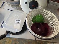 Overview showing salad spinner basket with green pepper container, maroon lids, clear lidded container and pan handle