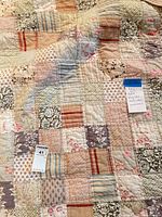Overall view of Pottery Barn king patchwork quilt showing multi-pattern squares and quilting