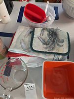 Group view showing measuring cup, scoop in bucket, potholder, towels, square bowls