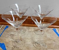 Four clear martini glasses standing on counter, full view
