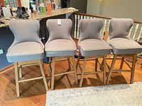 Front view of all four gray fabric bar stools lined up
