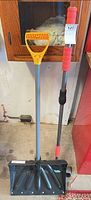 Snow shovel and telescoping ice scraper brush standing upright