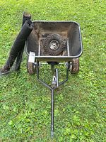 Top view of tow-behind spreader showing hopper interior, hitch tongue, tires, and garden mesh rolls