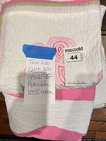 Stacked twin quilt sets showing folded design, tag indicates twin size and cotton content