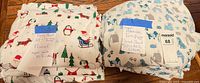 Two bundled sheet sets with labels indicating twin cotton flannel; holiday print on left, puppy print on right