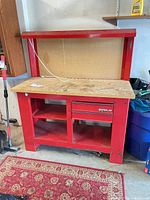 Front view of Waterloo red steel workbench showing pegboard, top, drawers and shelves
