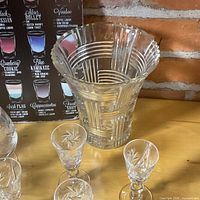 Overall view showing crystal vase with Pinwheel pattern, small cordials, and metal recipe sign background
