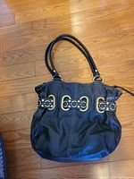 Full exterior view of black leather bag showing gold-tone hardware and handles