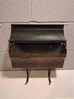 Frontal view showing open lid stamped F-1875, interior, and mounting legs
