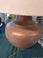 Side view of copper-tone metal lamp base beneath fabric shade