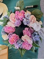 Front view of wreath showing full arrangement of artificial flowers and ribbon