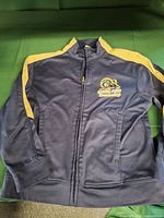 Front view of navy jacket with gold stripe and chest logo