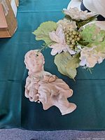Seated girl figurine lying beside artificial flowers