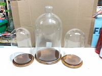 Front view of three glass domes with wood bases