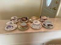 All eight teacup and saucer sets arranged on counter