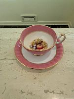 cup on saucer, front view showing pink exterior and fruit motif