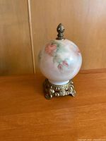 Front view of floral glass globe on brass base