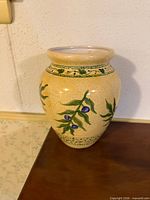 Front view of beige crackle-glazed ceramic vase with vine and berry motif