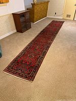 Full length view of red Persian runner laid on carpet