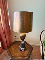 Full view of lamp on table showing gold drum shade and marble base
