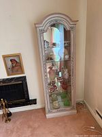 Front view of cabinet showing arched top, glass front, painted details