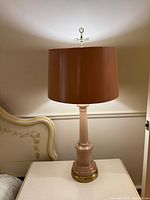 Entire lamp showing pink glass body, brass-tone base and brown shade