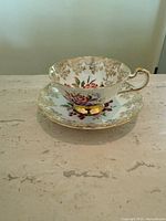Teacup on saucer showing gold gilt rims and floral motif