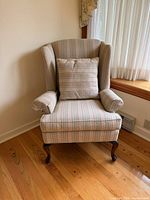 Front angled view of wingback chair showing upholstery, cushion, cabriole legs