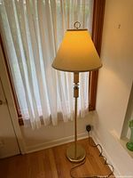 Full view of brass floor lamp, shade on, cord visible