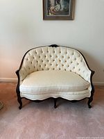 Front angled view showing button-tufted back, carved frame, cabriole legs