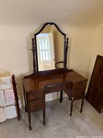 Front view of mahogany vanity showing mirror, drawers, legs