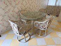 Oval glass-top rattan table and four matching chairs