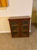 Front view of wood cabinet showing glass doors and shelves