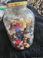 Full view of glass jar packed with assorted multicolor buttons