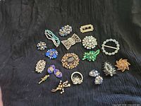 Full layout of 15 brooches on black fabric