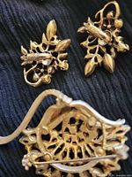 rear view of brooch and earrings showing gold-tone metal and clip mechanisms