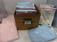 Box containing multiple sealed blue and pink Cardinal Health underpads with loose packaged sample