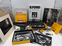 Overall lot showing Kodak and Ilford paper boxes, safelight filter, film rolls, prints and tray