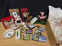 Group shot of all items including Lenox porcelain pieces, boxed items, reindeer, Santa wreath, ornaments, and tree kit