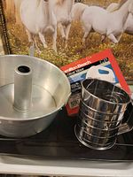 Group shot showing tube cake pan, hand mixer box, flour sifter, roasting pan