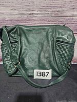 Front view of dark green Brio shoulder bag with woven side panels and strap
