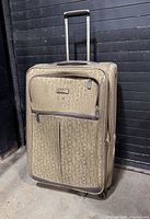 Full front view of beige Calvin Klein rolling suitcase with handle extended