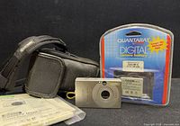 Group shot of camera, sealed battery, loose battery, case, manuals