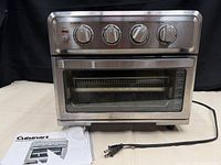 Front view of toaster oven with manual and power cord visible