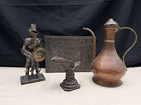 Group view of knight figurine, copper ewer, embossed plaque and ornate corbel stand