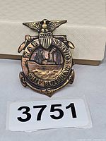 Front view of brass badge showing design and lettering