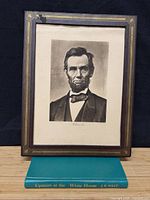 Full view of framed Abraham Lincoln print standing on book