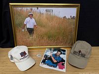 Group shot showing framed photo, signed photo and two caps