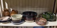 Shelf view showing all three stoneware bowls among other pottery